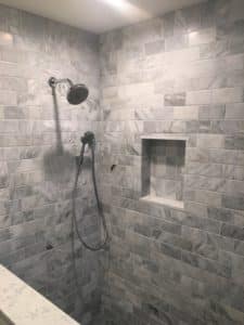 Features a large overhead showerhead and a handheld showerhead, as well as a built-in niche for storing bath products.